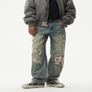 Men's distressed wide-leg denim jeans featuring plaid patch details.