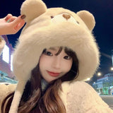 Woman wearing a cute plush bear winter hat with matching warm gloves in cream color.