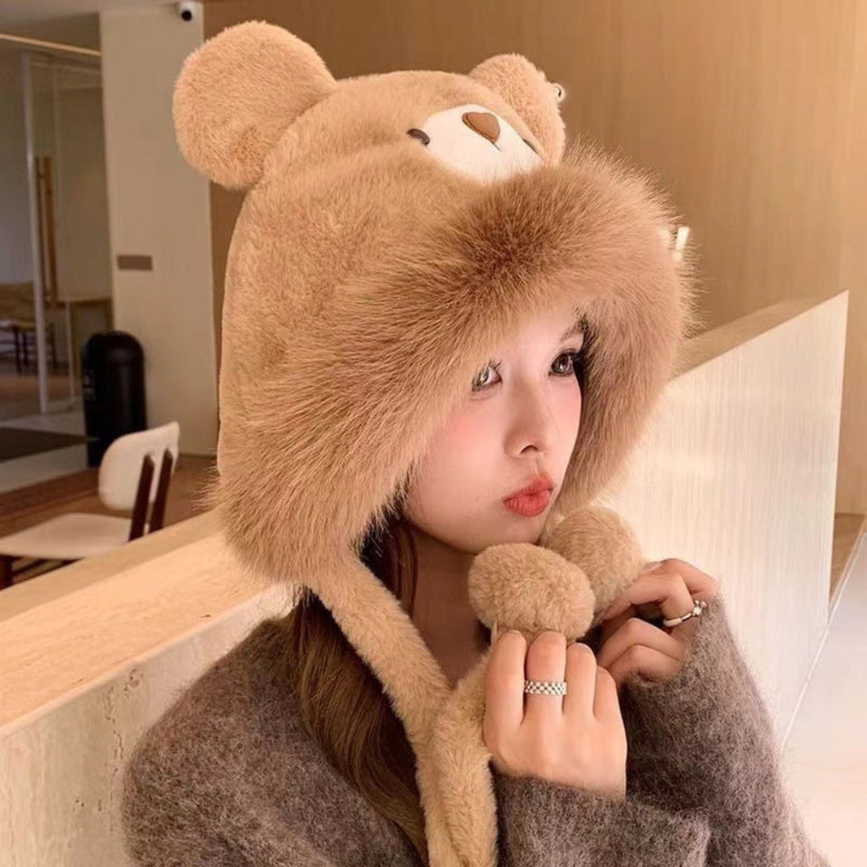 Woman wearing a cute plush bear winter hat with matching warm gloves in cream color.