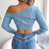 Woman wearing a blue off-shoulder long sleeve knit sweater with jeans.